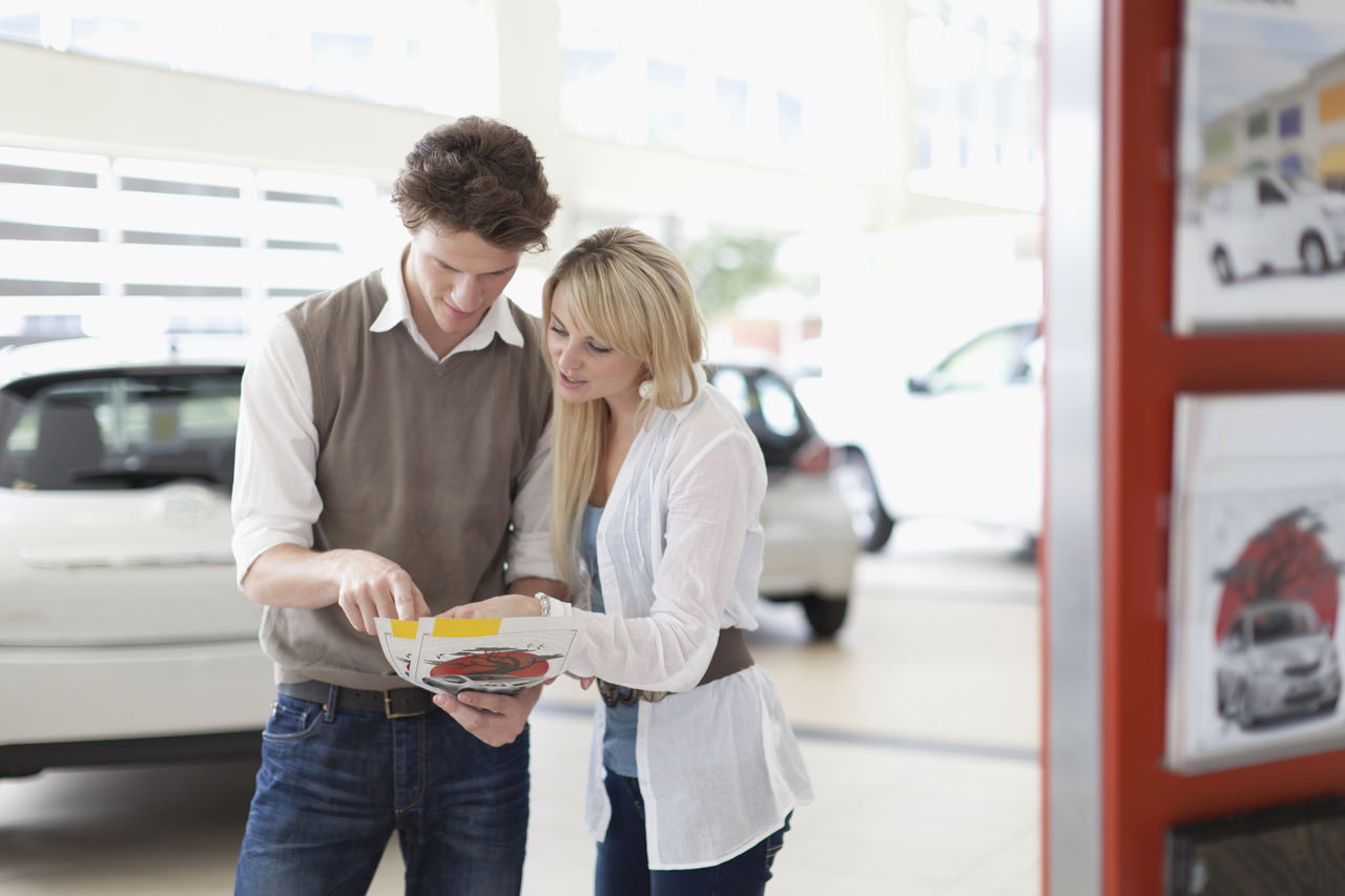 false couple comparing vehicles at car dealership