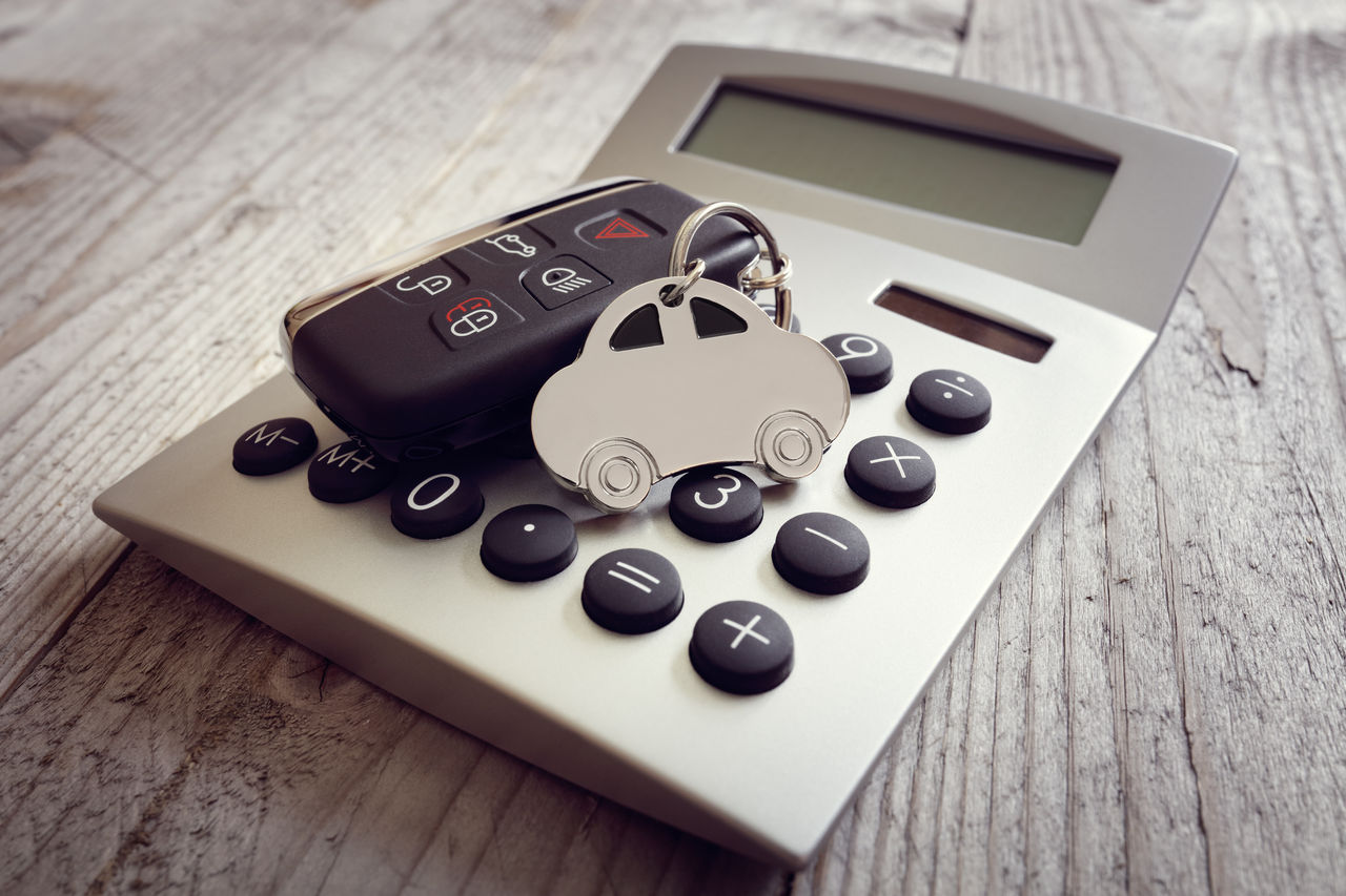 false Car shape keyring and key on calculator concept for motoring costs, finance, insurance, servicing or fuel bills