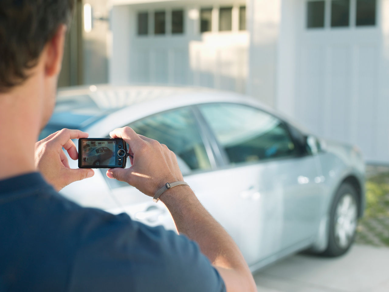 false man taking a photo of car in driveway