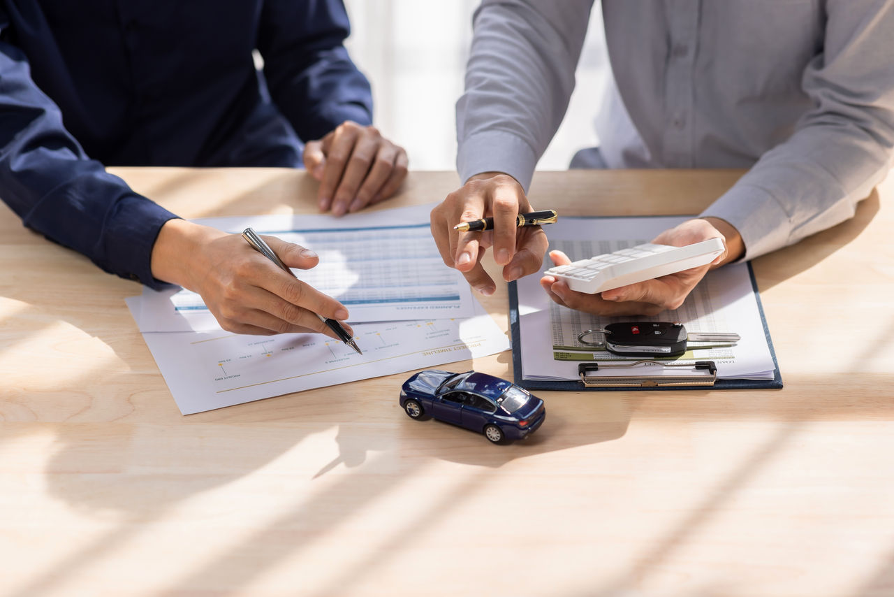 false Dealer salesman giving car key to owner. client signing insurance document or rental car lease form agreement contract Insurance car concept.