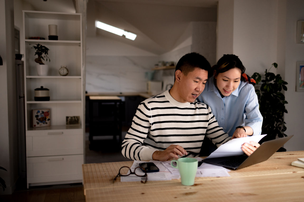 false Young Asian couple cooperating while going through their financial bills at home.