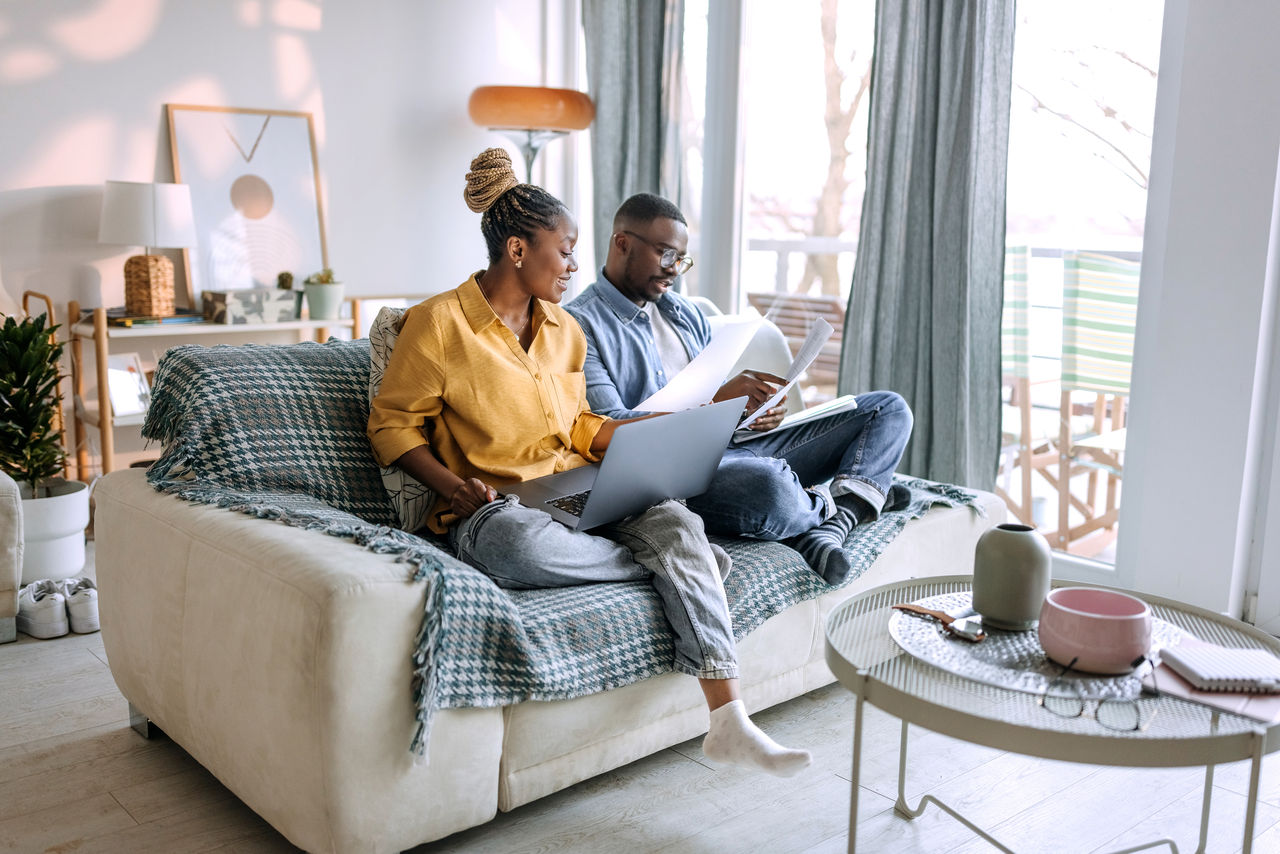 happy couple sitting on couch on computer