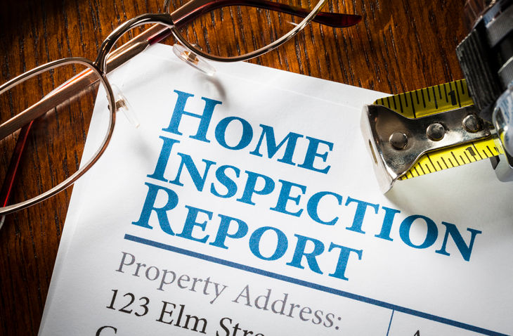 false Home Inspection Report with measuring tape and glasses on desk