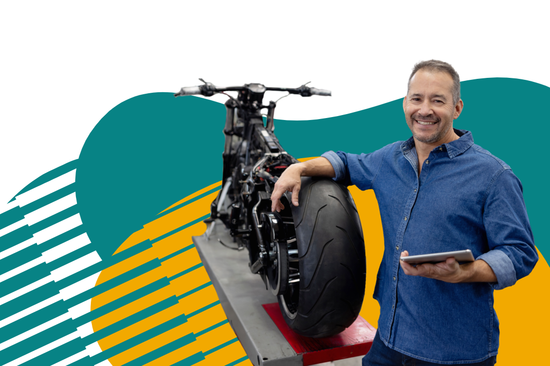 motorcycle shop owner standing next to motorcycle holding tablet