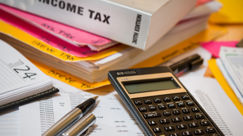 tax forms and binders with a pen scattered on a desk