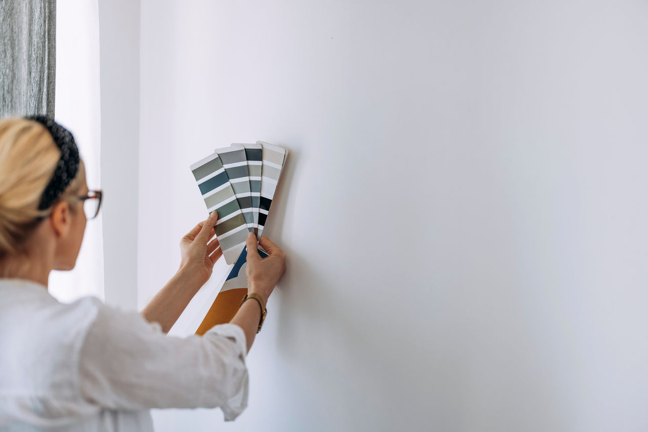 false Unrecognizable creative young architect looking at colour catalogue choosing paint palette for home interior and walls