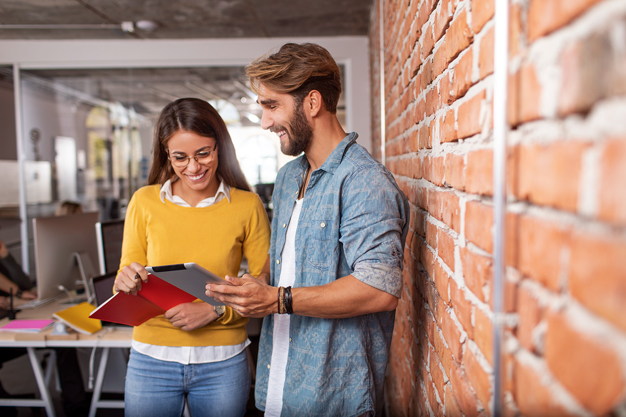 Young man showing something on his tablet to his female coworker